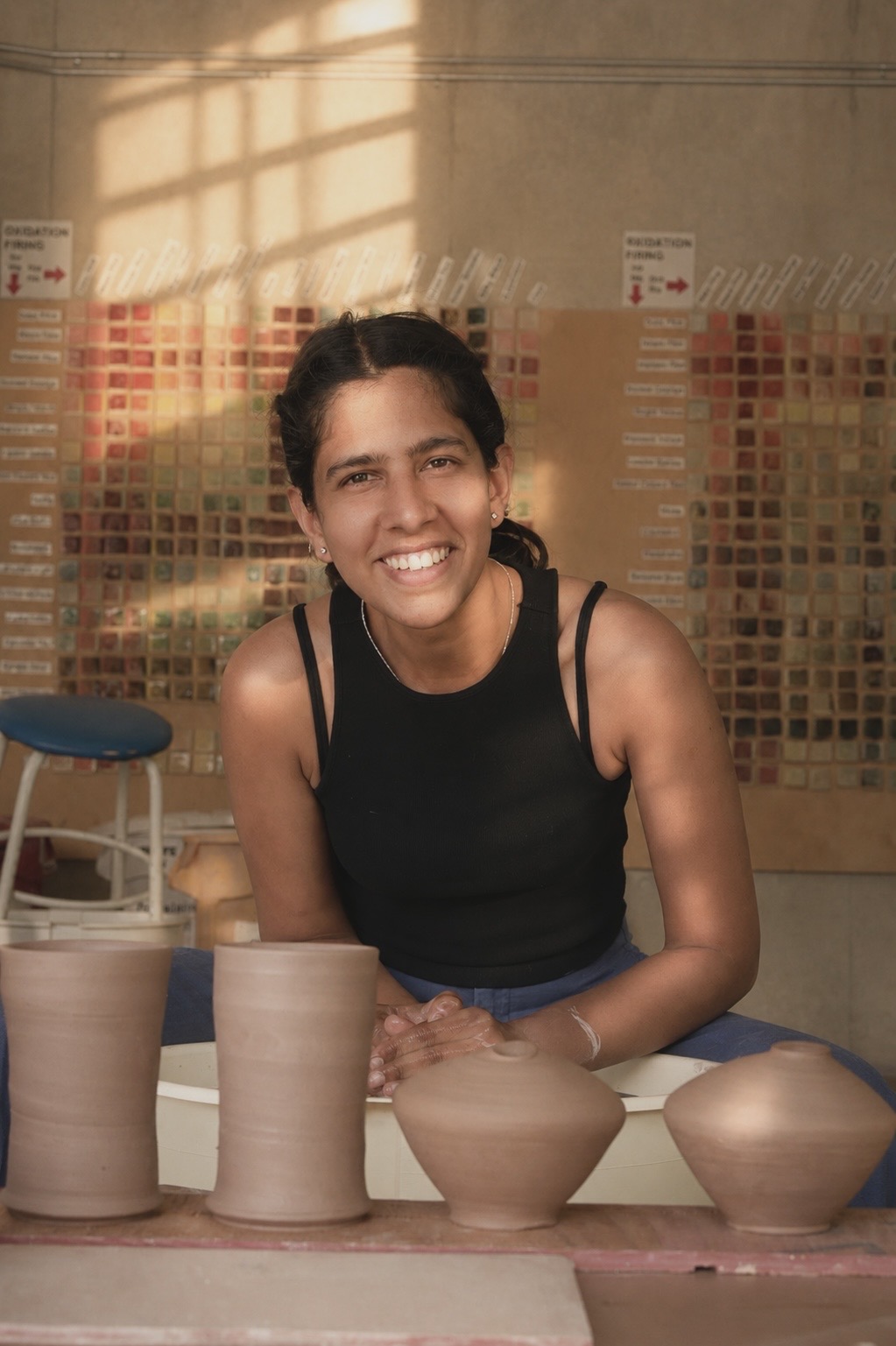 Shachi Shah seated in the ceramics studio with newly made vessels