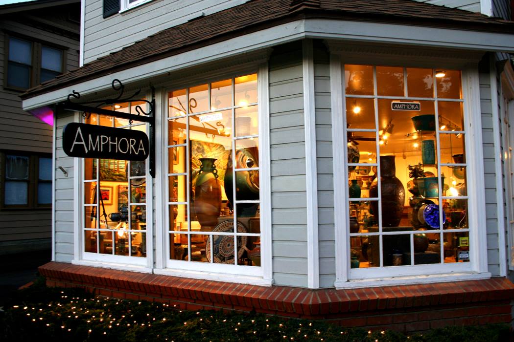 Amphora Gallery storefront at dusk, ceramics glowing in the corner windows