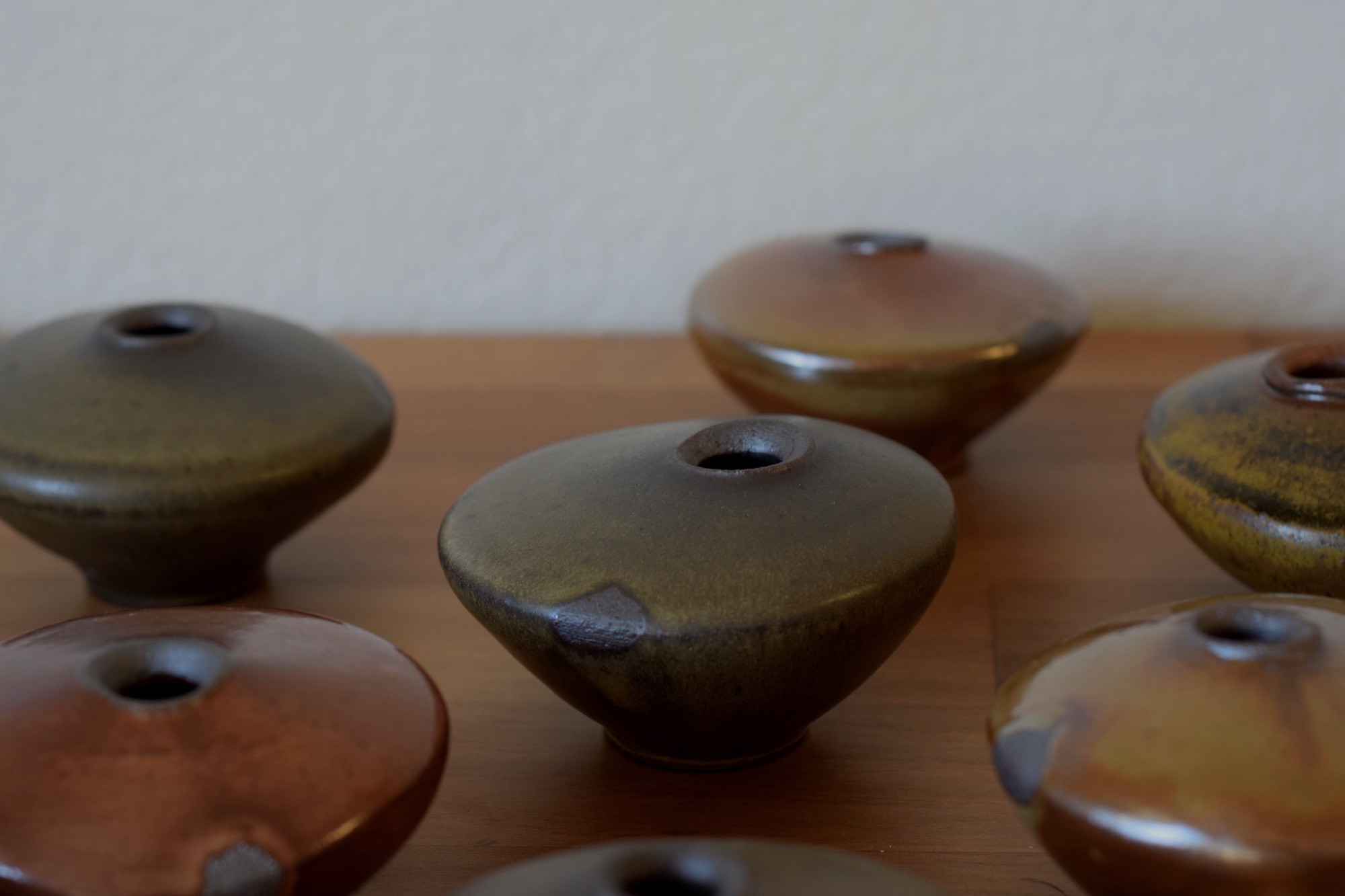 A group of rounded wood-fired bud vases arranged on a wooden surface