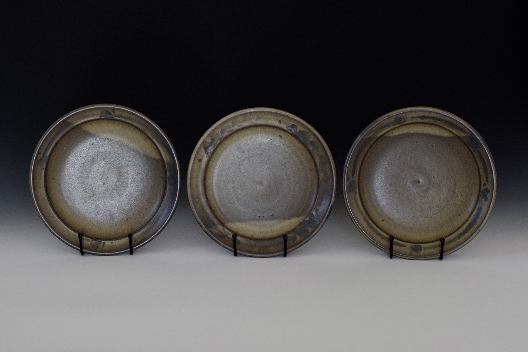 Three warm brown ceramic plates displayed upright